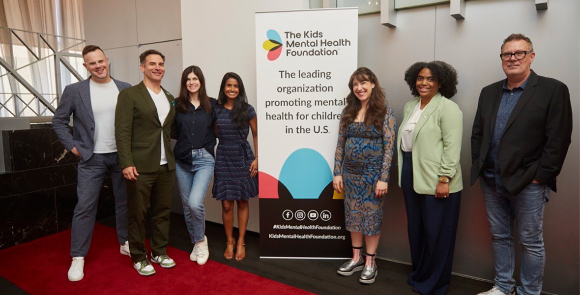 Andrew Levitt, known professionally as Nina West, poses with Kids Mental Health Foundation leaders and supporters at a mental health advocacy event.