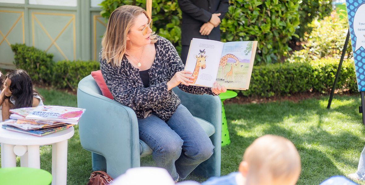 Actress Mädchen Amick reads a children’s book aloud during an outdoor storytime event hosted by The Kids Mental Health Foundation, engaging young listeners in a celebration of literacy and emotional connection.