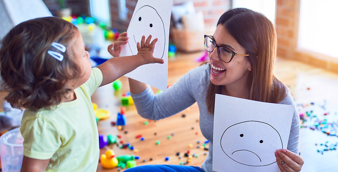 Young child and therapist using emotion flashcards to explore feelings in a play-based learning environment. Supporting children's emotional development and mental well-being through interactive activities.
