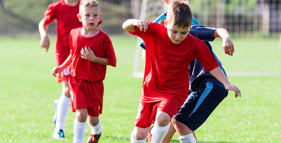 Young children playing soccer on a sunny day, building teamwork, confidence, and physical well-being. Sports and outdoor activities supporting kids' mental health and social skills.