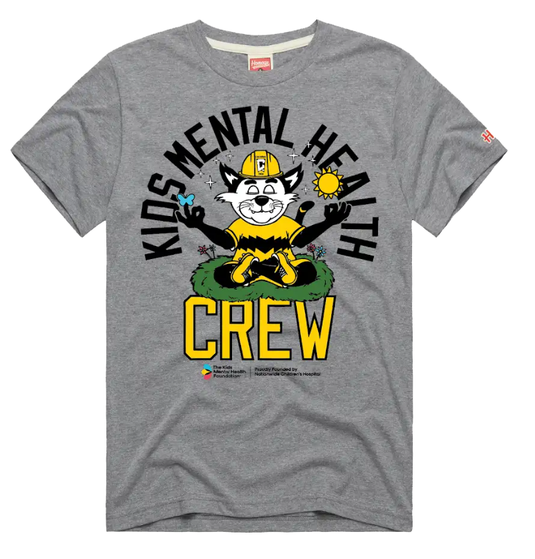 Gray t-shirt featuring a cartoon cat mascot in a construction helmet meditating on grass, with the text 'Kids Mental Health Crew' and logos for The Kids Mental Health Foundation and Nationwide Children’s Hospital. Design by HOMAGE.