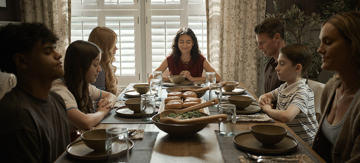 Family gathered around a dinner table in a scene from “It’s Not Like That,” showing a shared meal and moments of connection between parents and children