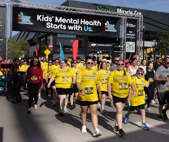 Los corredores lucen con orgullo sus medallas junto al trofeo del campeonato en el campo tras completar la carrera de 5 km «Por la salud mental infantil», lo que pone de relieve sus logros y el impacto en la comunidad.